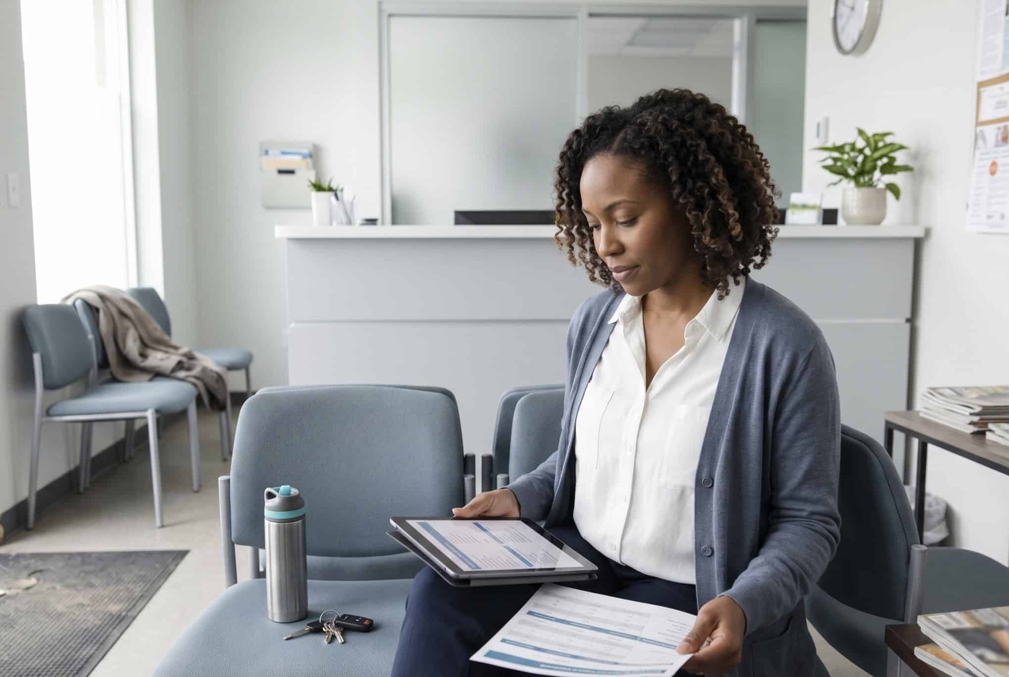 Adult comparing nationwide PPO health insurance plan options on a tablet at a modern clinic reception